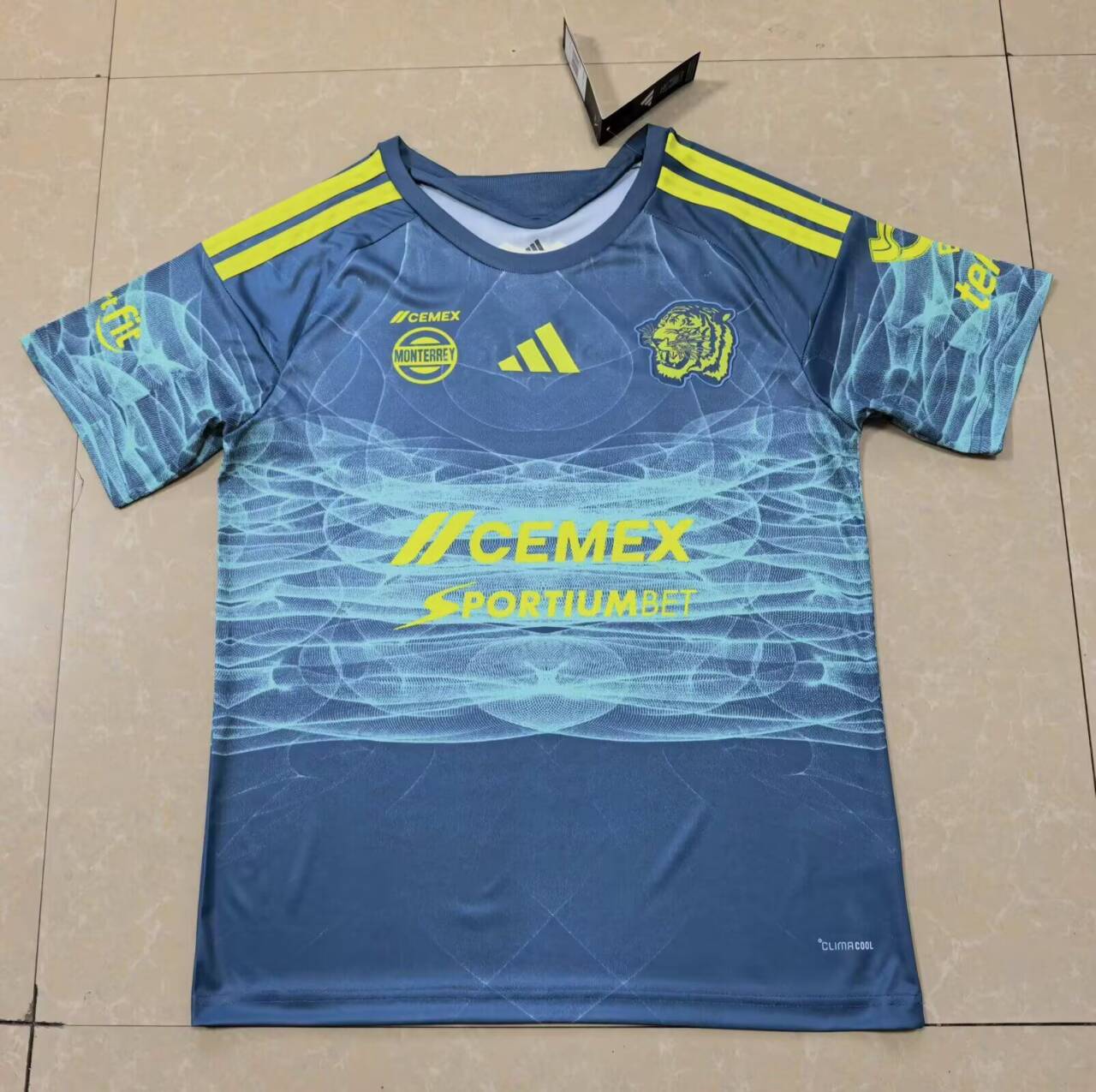 Front: blue body, aqua line pattern, tiger emblem and bright yellow chest and shoulder details.